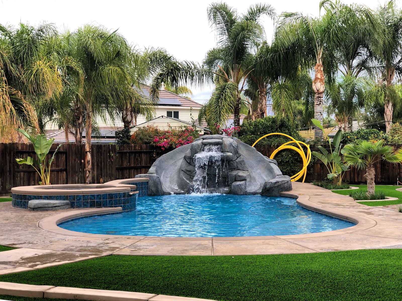 Backyard pool and spa with waterfall and turf